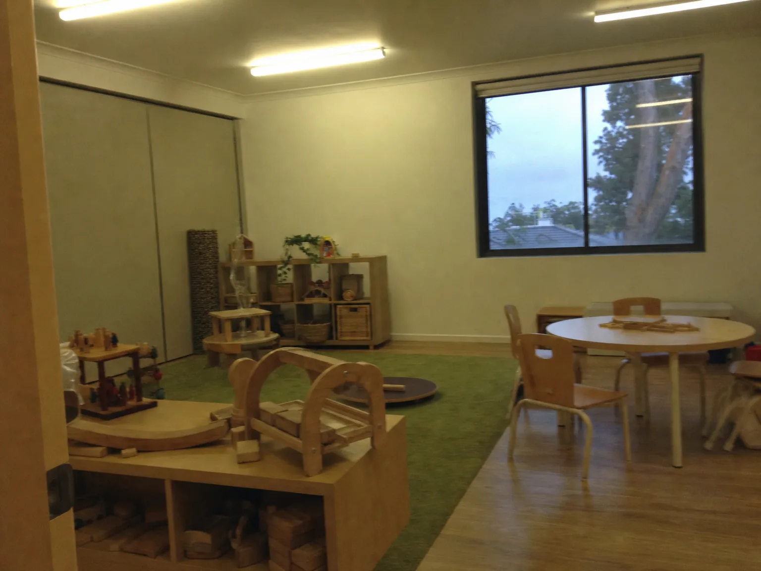 A dull, flat phone photo of a childcare playroom under fluorescent light